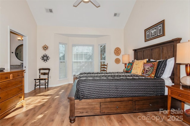 bedroom with light wood-type flooring, baseboards, visible vents, and vaulted ceiling