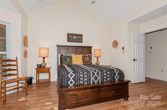 bedroom with vaulted ceiling, wood finished floors, and baseboards