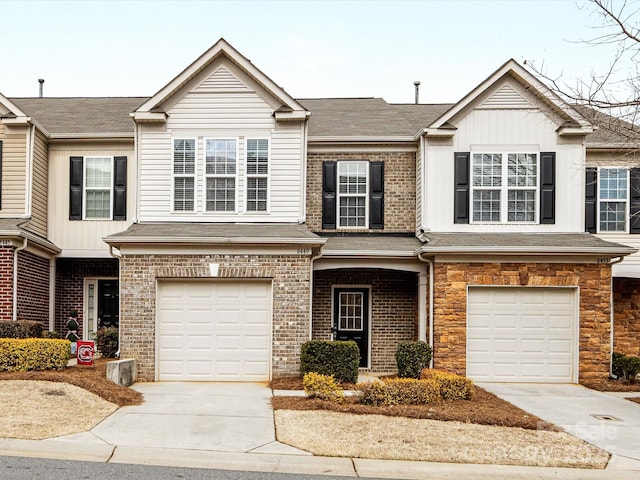 townhome / multi-family property featuring board and batten siding, brick siding, driveway, and an attached garage