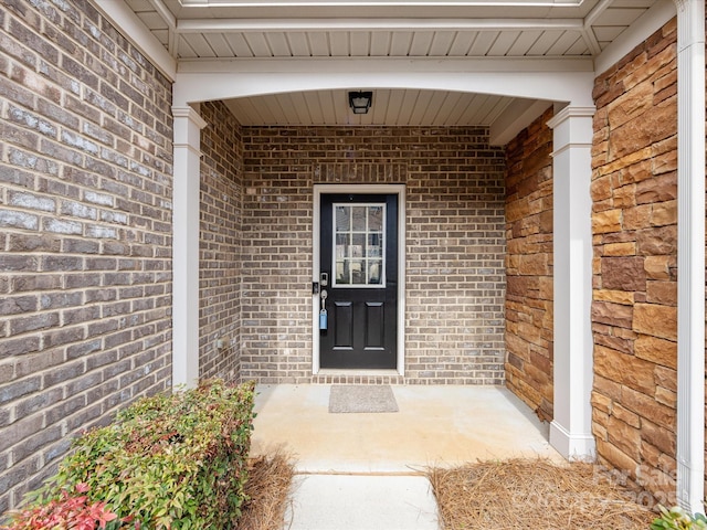 property entrance with a porch and brick siding