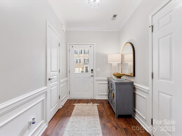 entryway featuring a wainscoted wall, crown molding, visible vents, and dark wood-type flooring