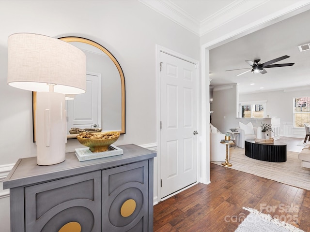 interior space featuring visible vents, wainscoting, ceiling fan, ornamental molding, and dark wood-type flooring