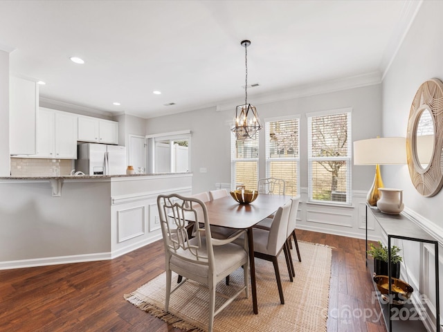 dining area with ornamental molding, a wainscoted wall, dark wood finished floors, and a decorative wall