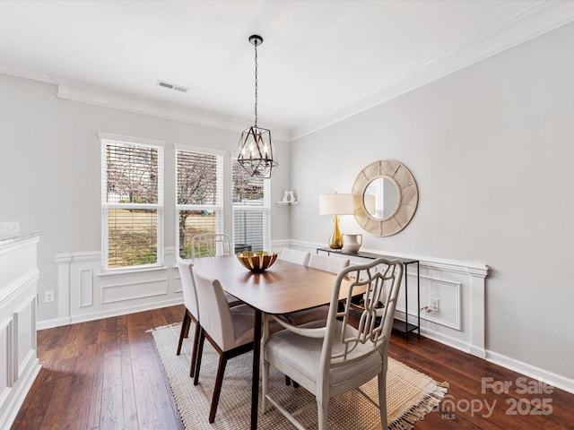 dining room featuring wood-type flooring, visible vents, crown molding, and an inviting chandelier