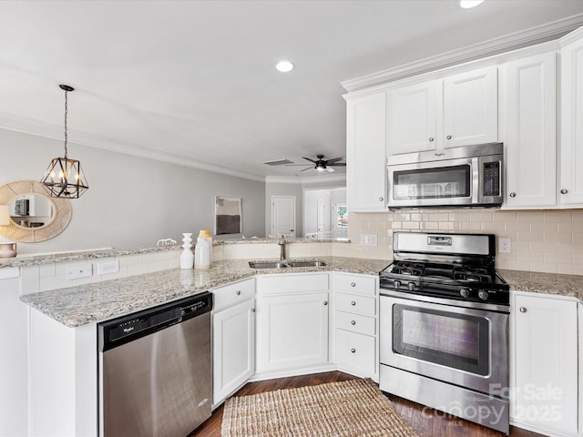 kitchen featuring stainless steel appliances, a sink, white cabinetry, decorative backsplash, and crown molding