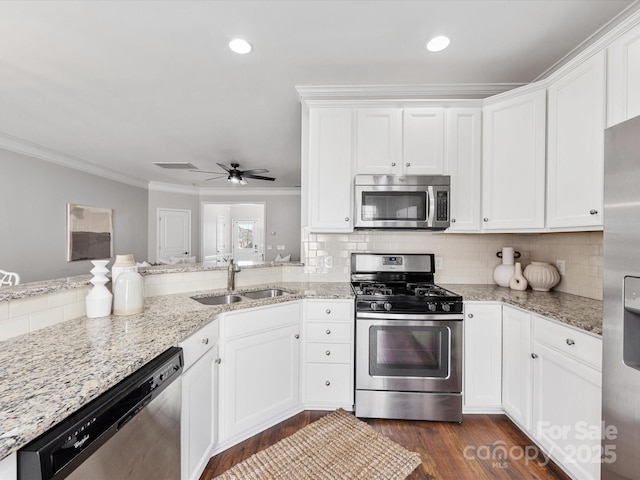 kitchen featuring crown molding, tasteful backsplash, appliances with stainless steel finishes, white cabinets, and a sink