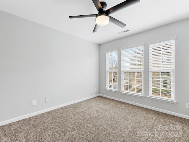 carpeted spare room featuring a ceiling fan, visible vents, and baseboards