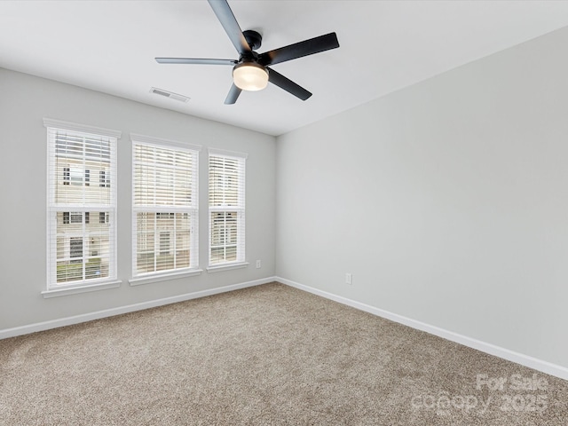 empty room with a wealth of natural light, carpet flooring, and visible vents