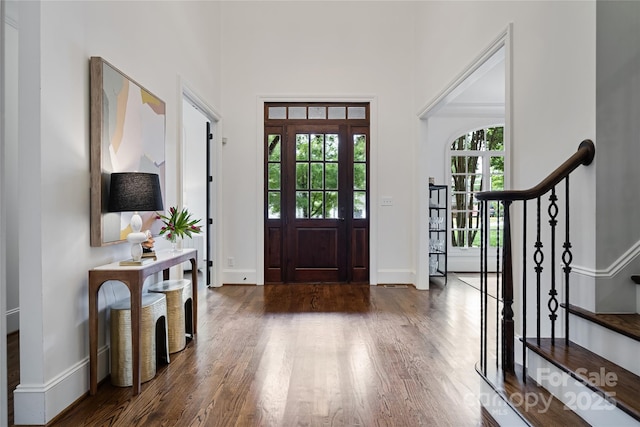 foyer entrance featuring a high ceiling, stairway, wood finished floors, and baseboards