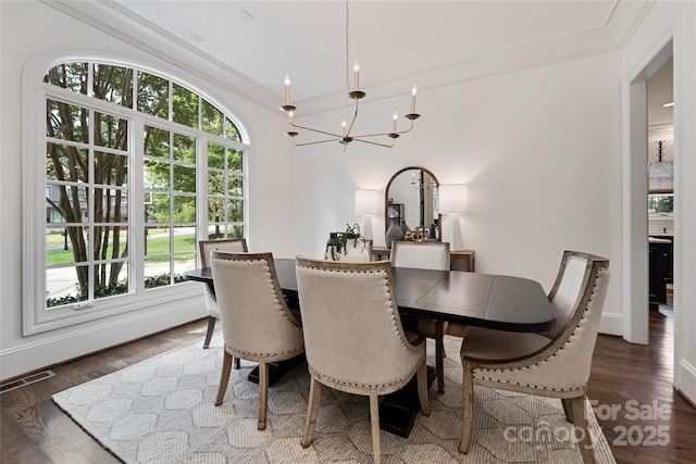 dining area with visible vents, a chandelier, wood finished floors, and ornamental molding