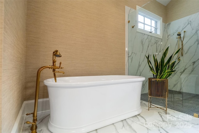 bathroom with marble finish floor and a freestanding tub