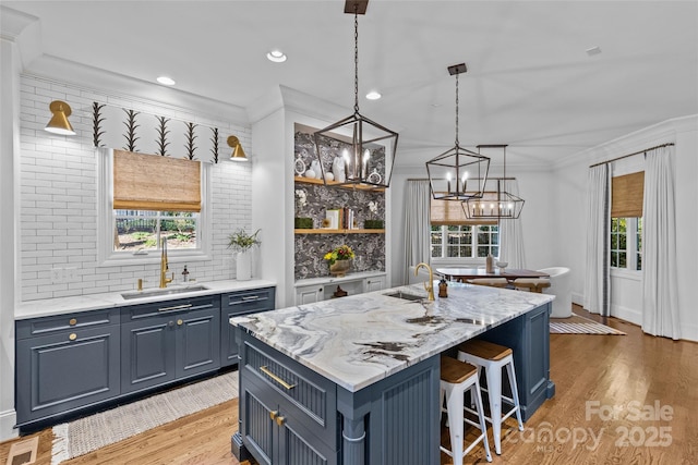 kitchen with ornamental molding, blue cabinetry, light wood finished floors, and a sink