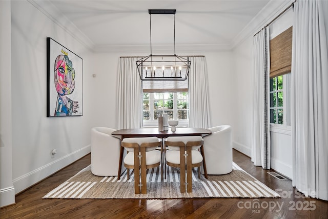 dining space featuring visible vents, ornamental molding, wood finished floors, a chandelier, and baseboards