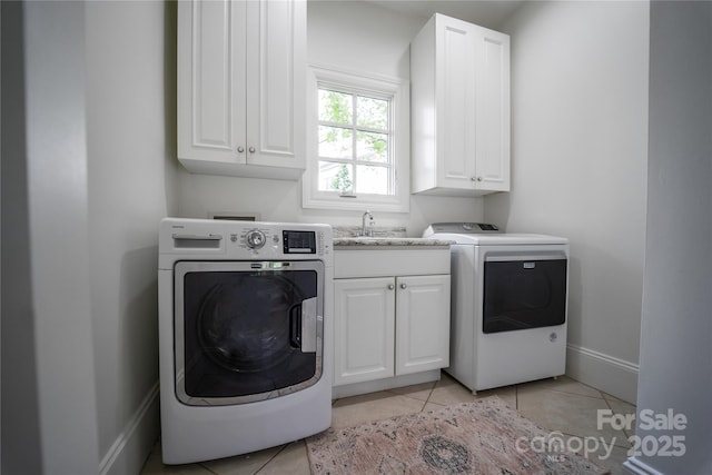 laundry area featuring cabinet space, baseboards, washer and dryer, and light tile patterned flooring