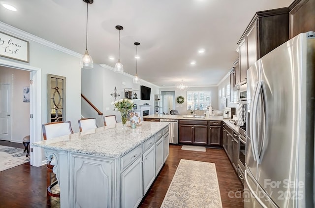 kitchen featuring appliances with stainless steel finishes, crown molding, a kitchen breakfast bar, and a sink