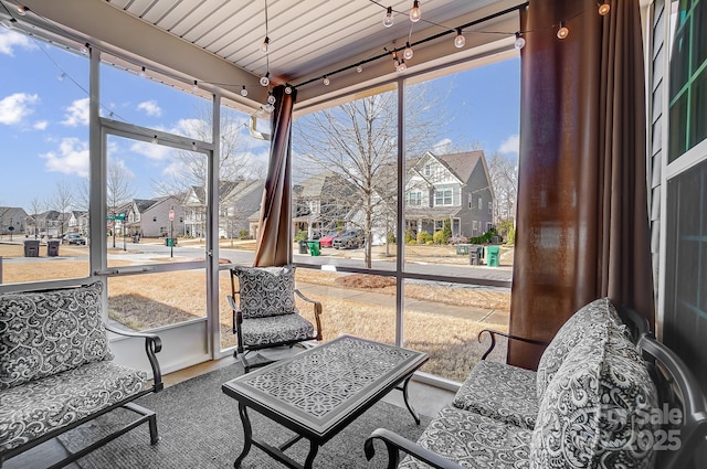 sunroom featuring a wealth of natural light, a residential view, and track lighting