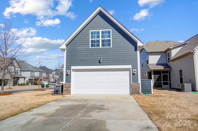 view of front facade featuring central air condition unit, a garage, brick siding, and driveway