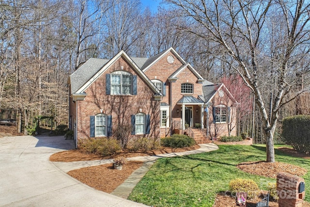 traditional-style house with a front yard, concrete driveway, and brick siding