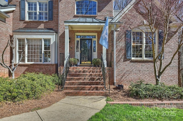 view of exterior entry with a standing seam roof, metal roof, and brick siding