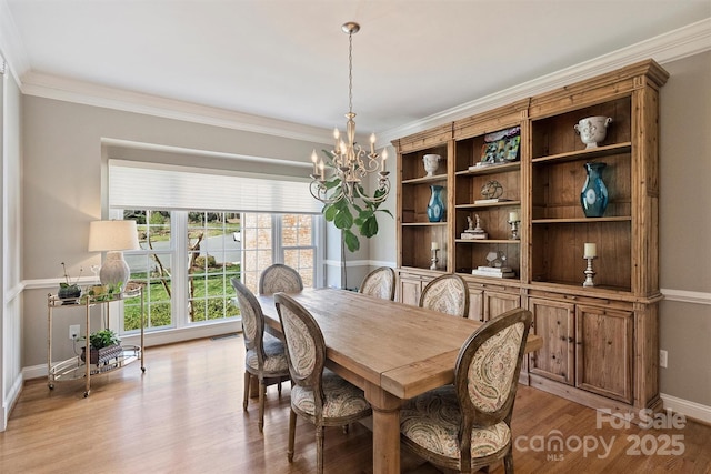 dining room with ornamental molding, light wood-type flooring, a notable chandelier, and baseboards