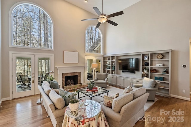 living room featuring a towering ceiling, a fireplace, wood finished floors, and a wealth of natural light