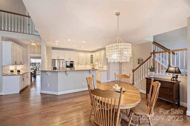 dining room featuring baseboards, stairway, an inviting chandelier, light wood-style floors, and recessed lighting