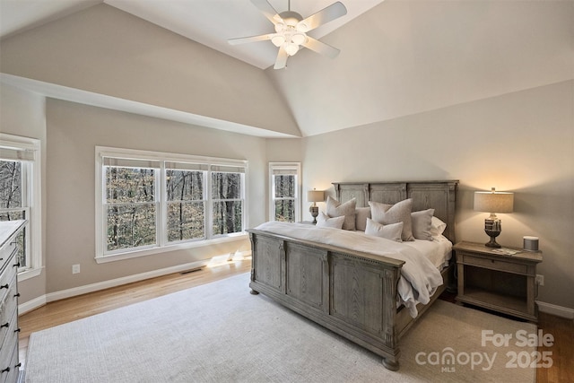 bedroom with high vaulted ceiling, visible vents, light wood-style flooring, and baseboards