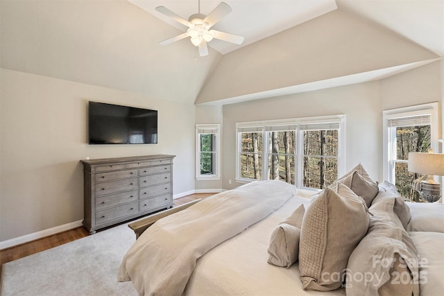 bedroom with lofted ceiling, multiple windows, baseboards, and wood finished floors