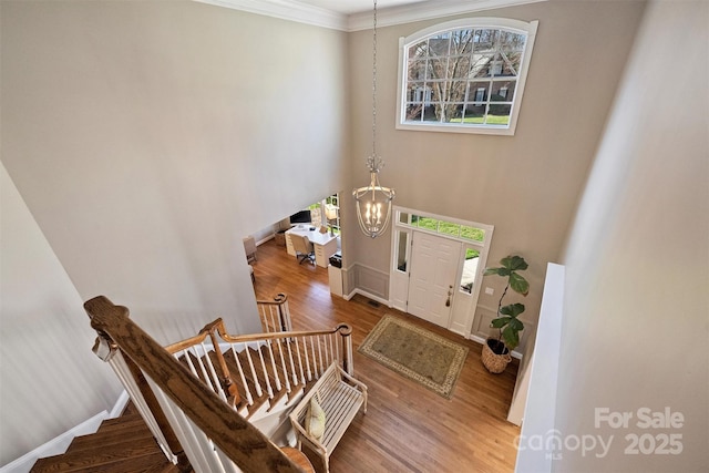 foyer entrance featuring baseboards, stairs, a chandelier, and wood finished floors