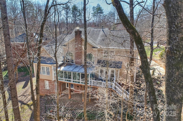 back of house with roof with shingles, stairway, a chimney, and brick siding