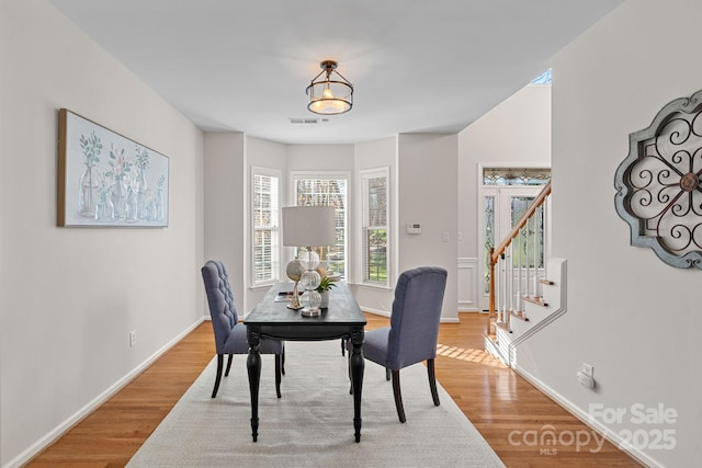 dining room featuring stairs, wood finished floors, visible vents, and baseboards