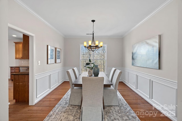 dining area featuring crown molding, wood finished floors, visible vents, and a notable chandelier