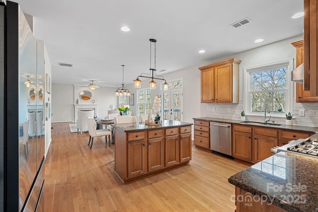 kitchen featuring brown cabinetry, a fireplace, dishwasher, and a sink