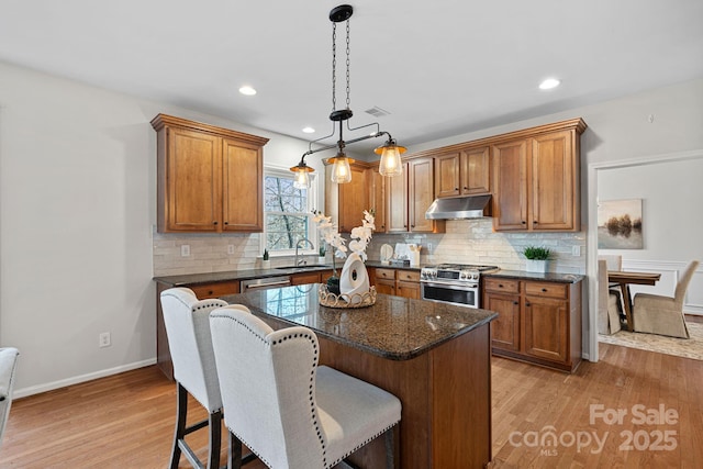 kitchen featuring appliances with stainless steel finishes, brown cabinets, a sink, and under cabinet range hood