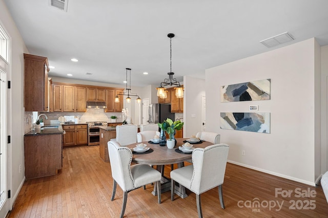 dining space featuring light wood finished floors, recessed lighting, visible vents, and baseboards