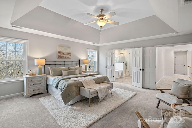 bedroom featuring a raised ceiling, light carpet, and visible vents