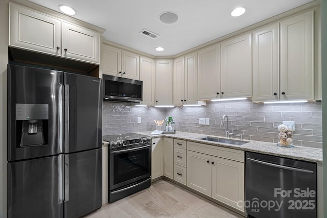 kitchen featuring cream cabinets, visible vents, appliances with stainless steel finishes, and a sink