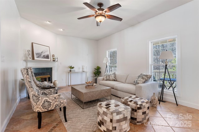 living room with a healthy amount of sunlight, a fireplace, baseboards, and a ceiling fan