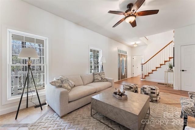 living area with a ceiling fan, visible vents, stairway, and baseboards