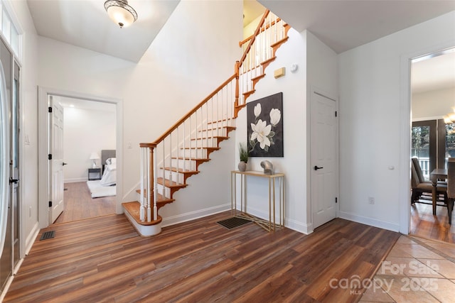 entrance foyer featuring dark wood-type flooring, stairway, and baseboards