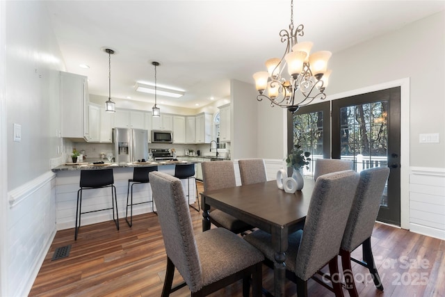 dining area featuring a wainscoted wall, dark wood-style floors, visible vents, and a chandelier