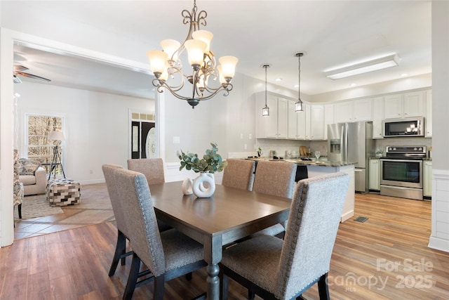 dining space featuring recessed lighting, baseboards, visible vents, light wood-style floors, and ceiling fan with notable chandelier