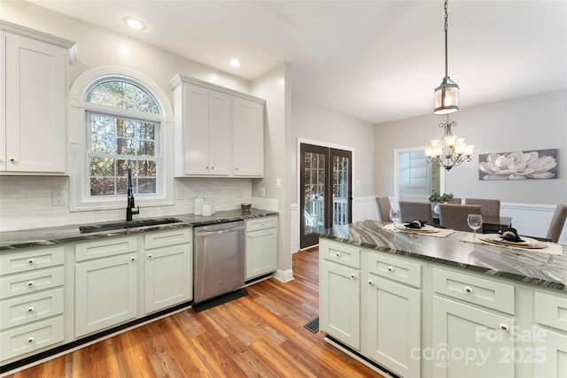 kitchen featuring wood finished floors, a sink, dishwasher, tasteful backsplash, and pendant lighting