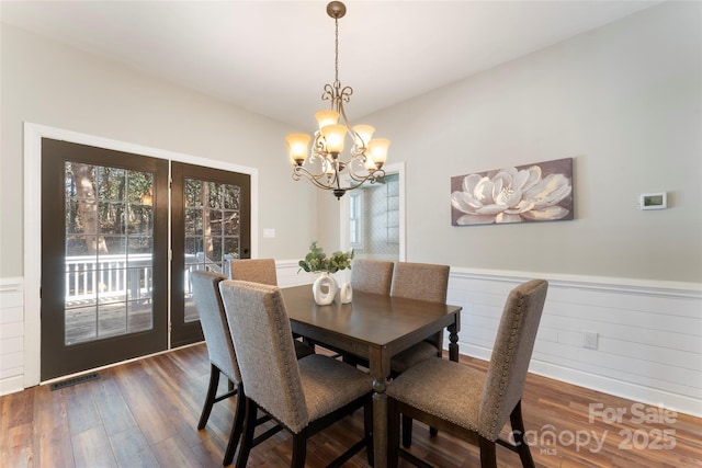 dining area with a wainscoted wall, visible vents, dark wood-style floors, and a notable chandelier