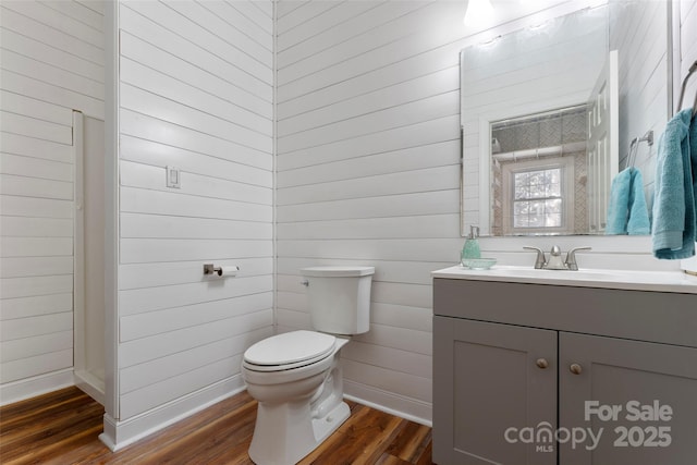 bathroom featuring toilet, baseboards, wood finished floors, and vanity