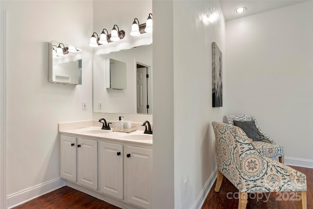 bathroom with double vanity, baseboards, a sink, and wood finished floors