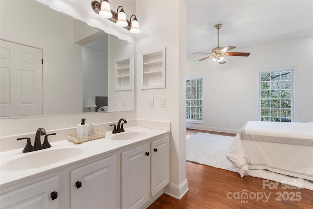 bathroom featuring double vanity, ceiling fan, a sink, and wood finished floors