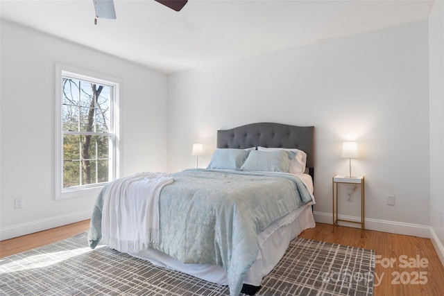 bedroom with a ceiling fan, baseboards, and wood finished floors