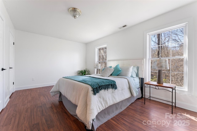 bedroom featuring multiple windows, visible vents, and dark wood-type flooring