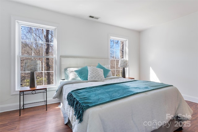 bedroom with dark wood-style flooring, visible vents, and baseboards